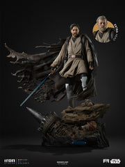 Star Wars – Obi-Wan Kenobi Signatures Legacy Replica 1:4  (Iron Studios). Star Wars Iron Studios Collect Obi-Wan Kenobi 1/6 scale collectible statue on a dark rocky base, featuring a flowing dark cloak, beige tunic, gray boots, and a blue lightsaber, with an extra head insert shown in the upper right.