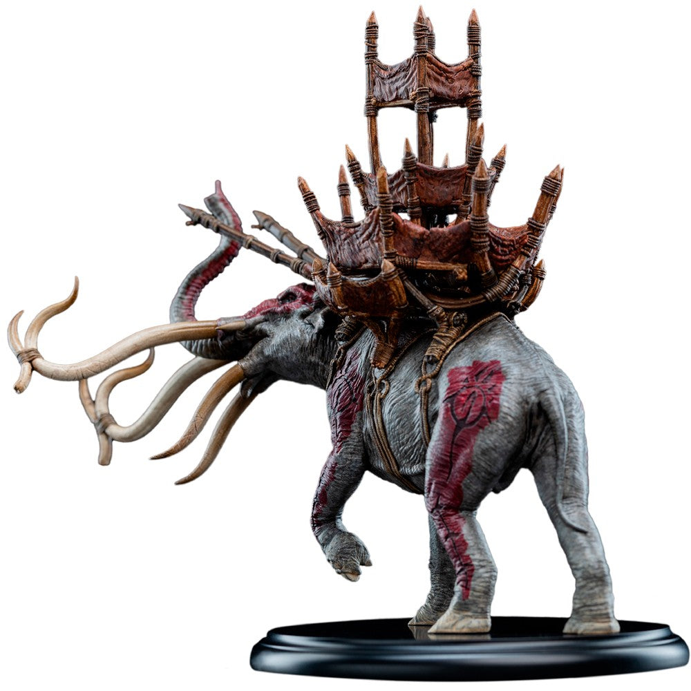 A fantasy miniature figurine of a mammoth-like creature carrying a large, ornate, multi-tiered tower-like structure on its back, mounted on a black circular base against a plain white background. LORD OF THE RINGS - Mumak in Battle 1:20 Statue (Weta Workshop)