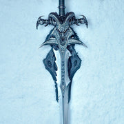 Frostmourne Sword Replica Scale 1/1 - World of Warcraft Cursed Sword of the Lich King. A fantasy-style sword with an ornate ram skull hilt and detailed silver blade, photographed upright against a pale icy blue textured background.