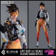 Life size 1:1 scale silicone human replica of Overwatch's Tracer by Cursed Collectibles, shown in a split-screen presentation with a close-up on the left and a full-body view on the right against a dark gray background. This is not a Overwatch tracer sex doll (but can be upgraded).